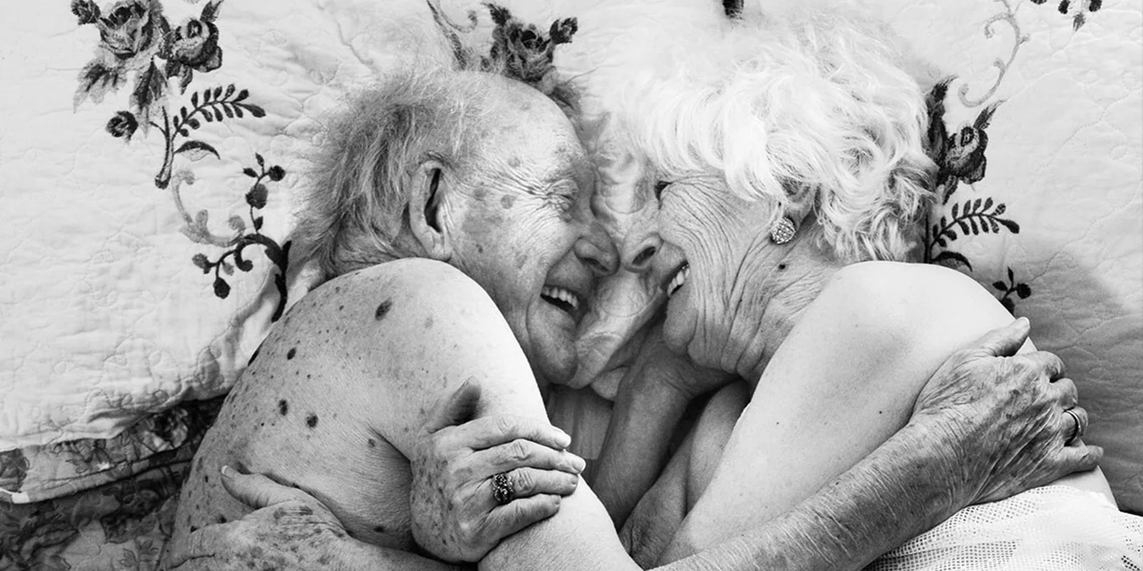 An older couple embracing intimately in bed.