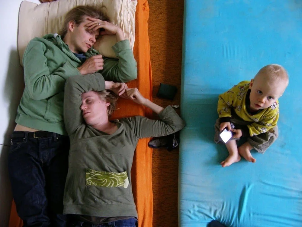 Two exhausted new parents lying awake in bed, too tired for intimacy.