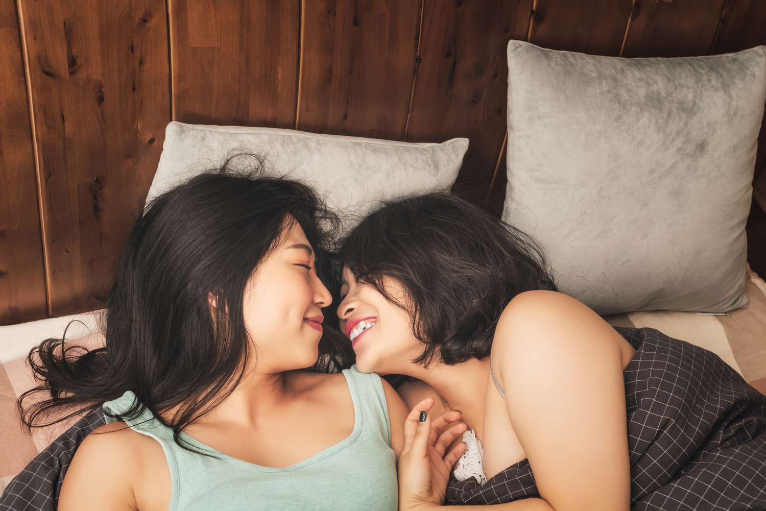 Two women lying close together and smiling, illustrating attraction and intimacy between women.