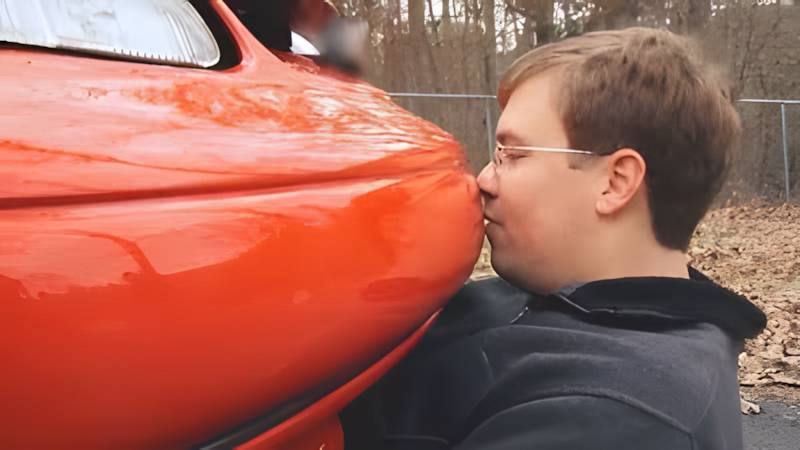 A person embracing a car, illustrating a strong emotional and sexual bond with an inanimate object.