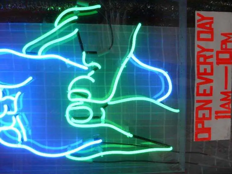 Neon window sign showing hands massaging a back, glowing at night.
