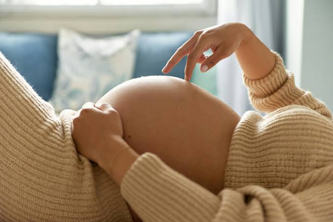 A person in the third trimester with a large pregnant belly.