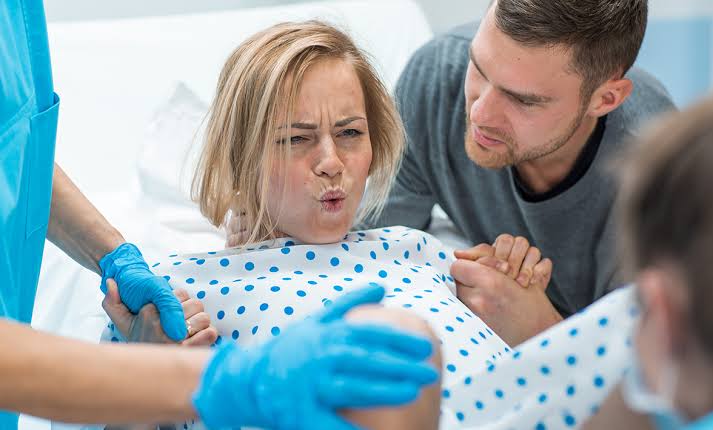 A person pushing during the second stage of labor, supported by a partner.