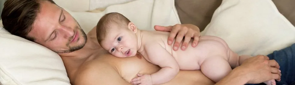 A parent holding their newborn against their bare chest in skin-to-skin contact.