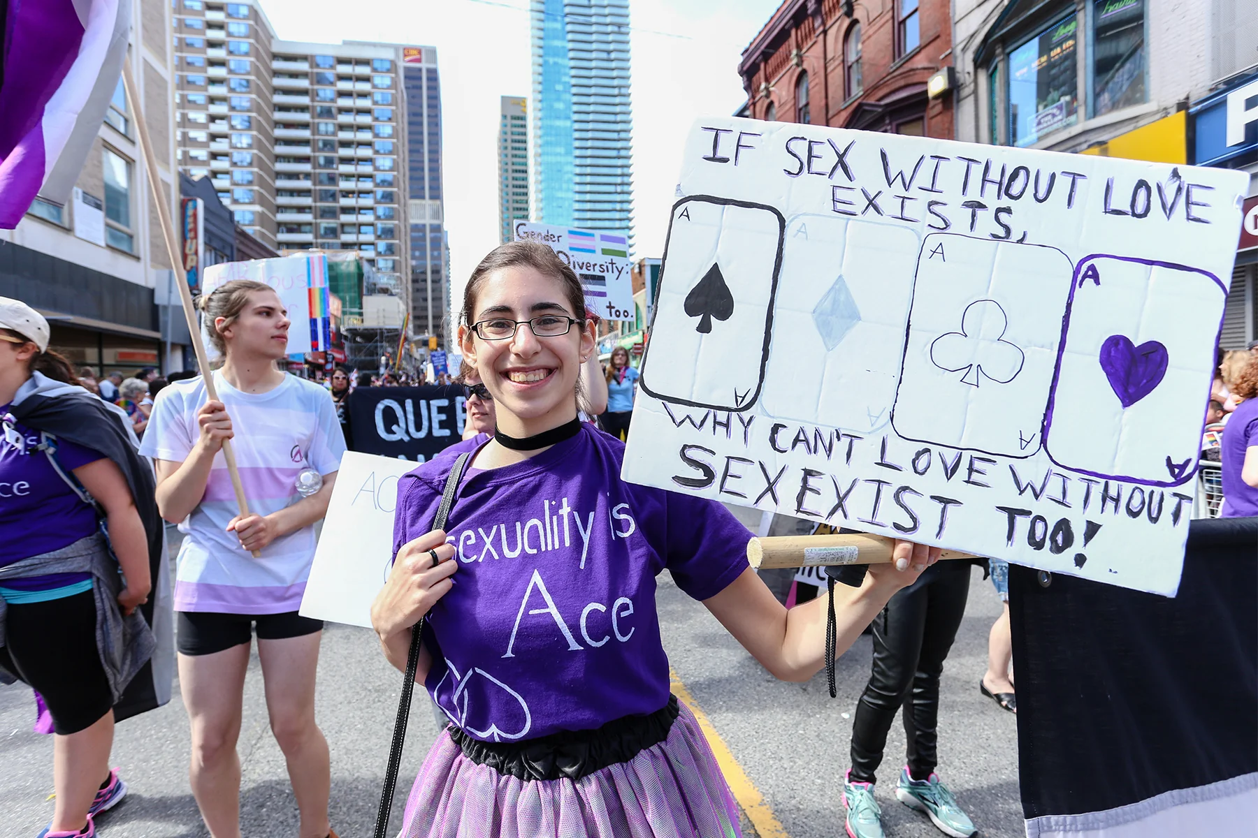 People at a rally holding signs and the asexual pride flag, promoting awareness and acceptance of asexuality.